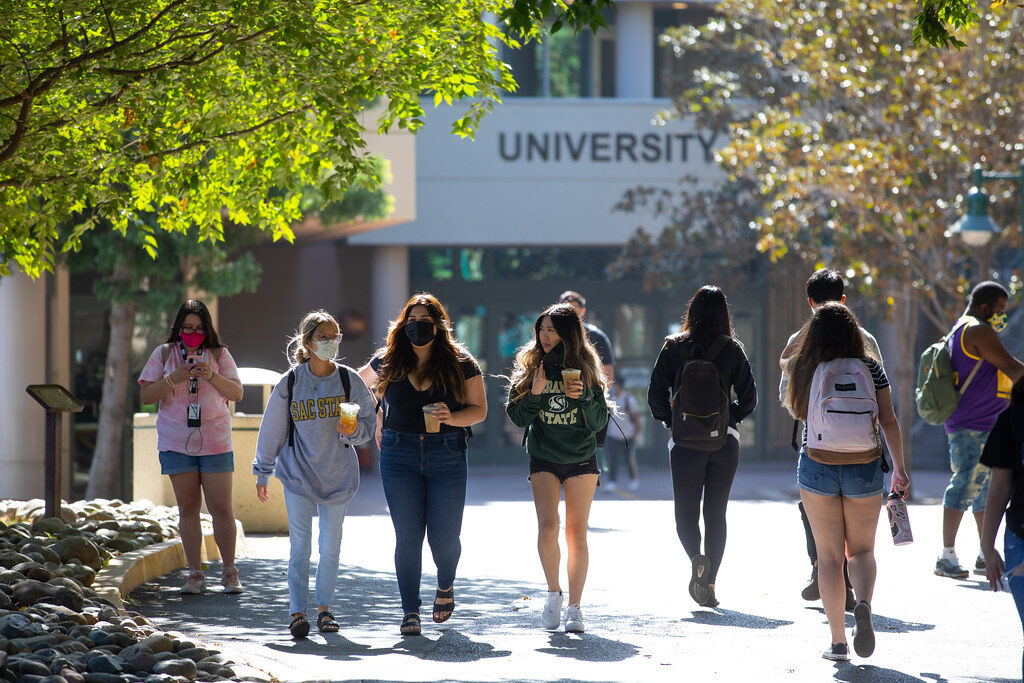 Students walking through a sunlit traditional British university campus courtyard